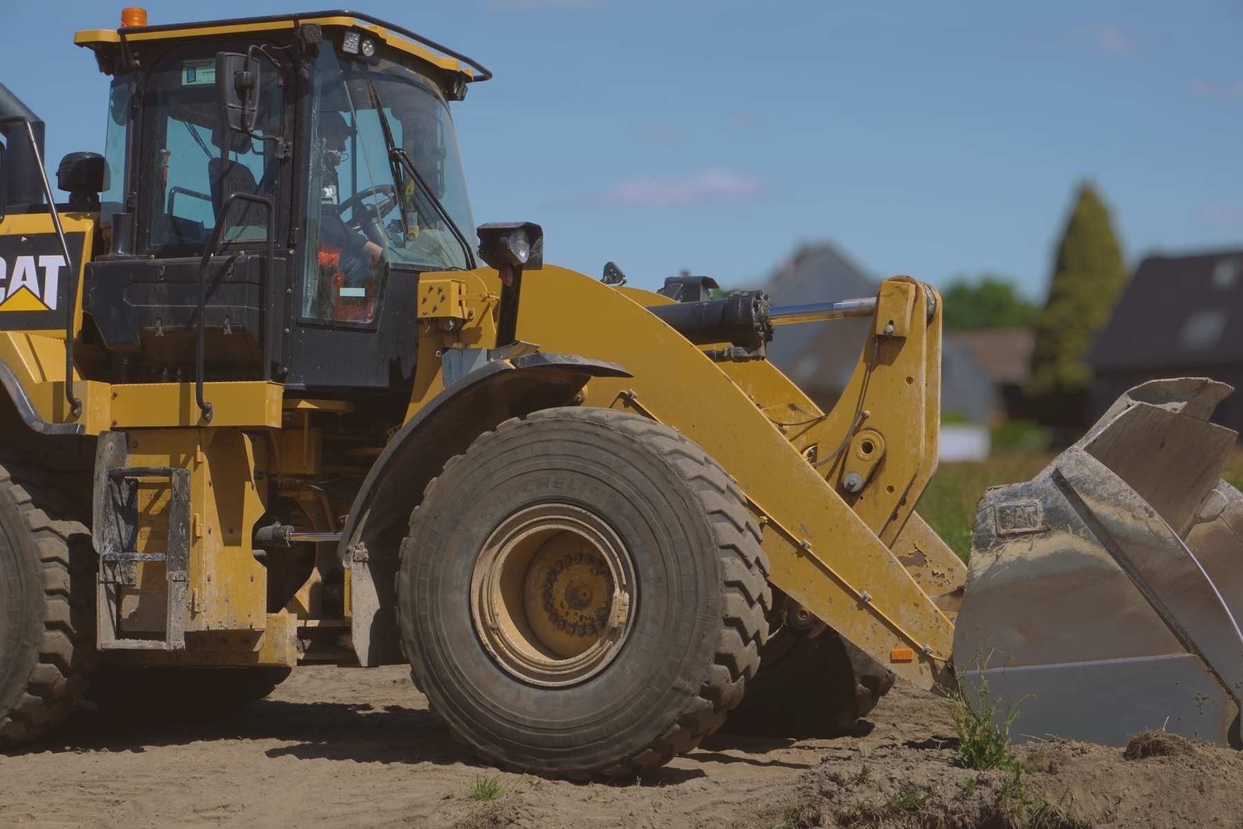 Radlader mit Schaufel bewegt Erdreich auf einer Baustelle.