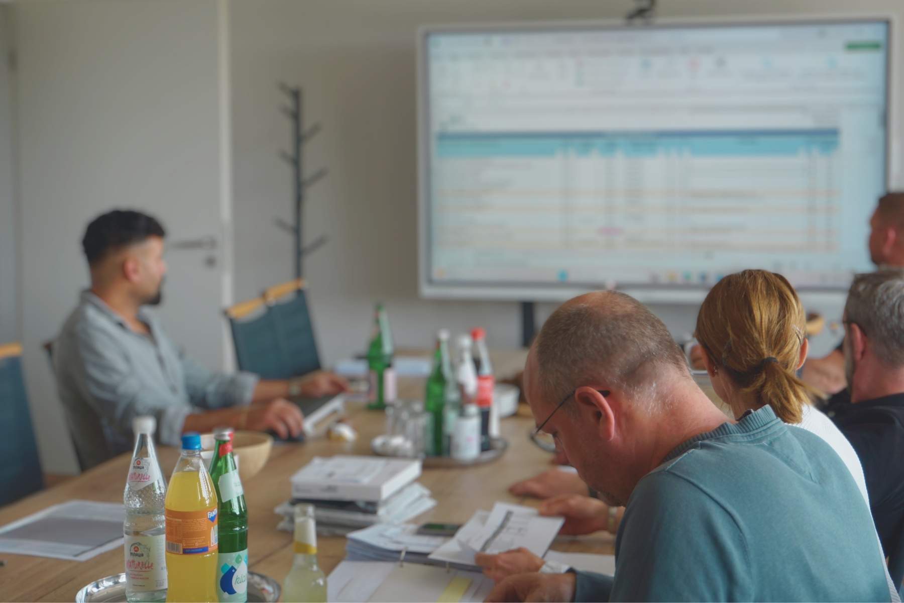 Team im Besprechungsraum arbeitet an Projektdaten auf der Leinwand