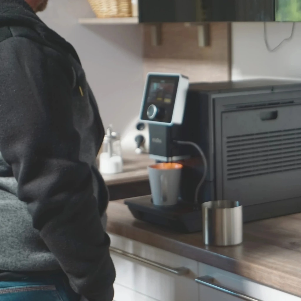 Mitarbeiter bereitet an der Kaffeemaschine eine Tasse zu
