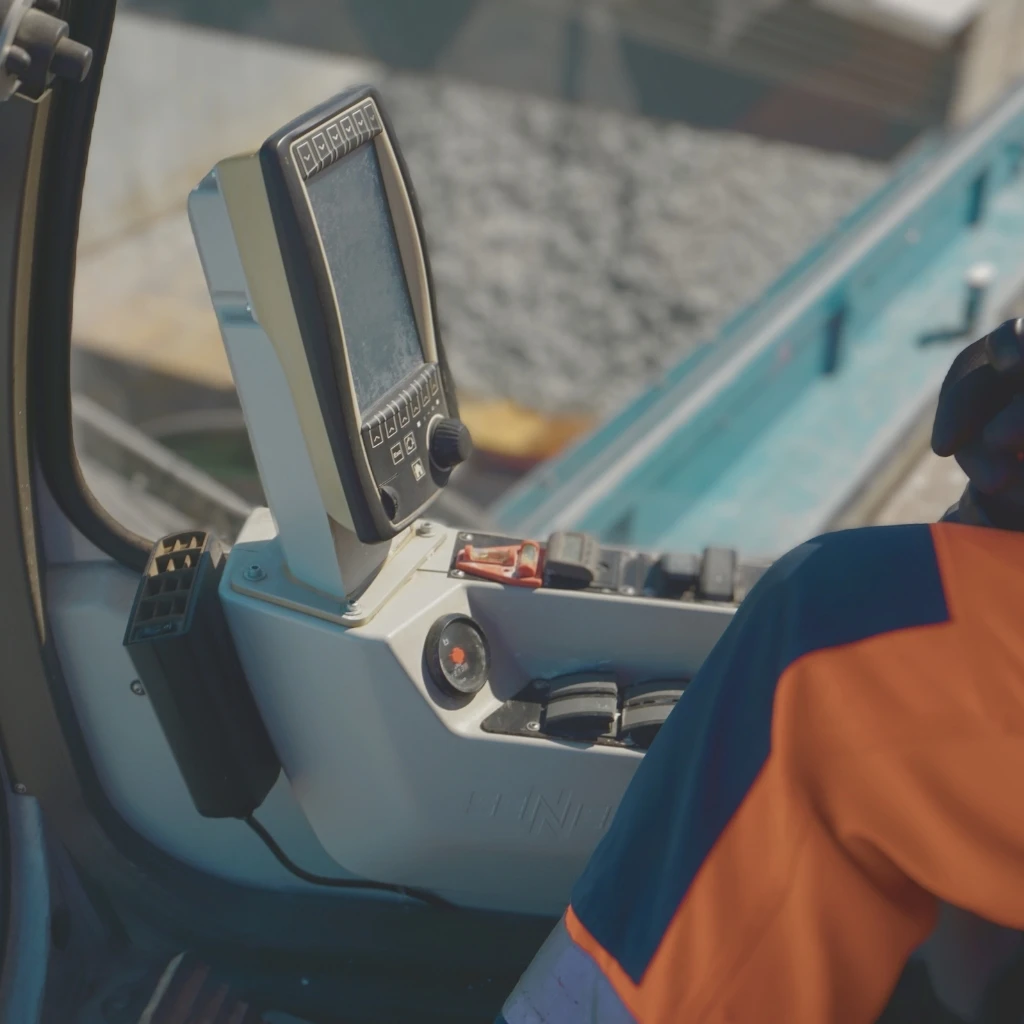 Bedienpult in der Kabine einer Baumaschine mit Hand am Steuerknüppel