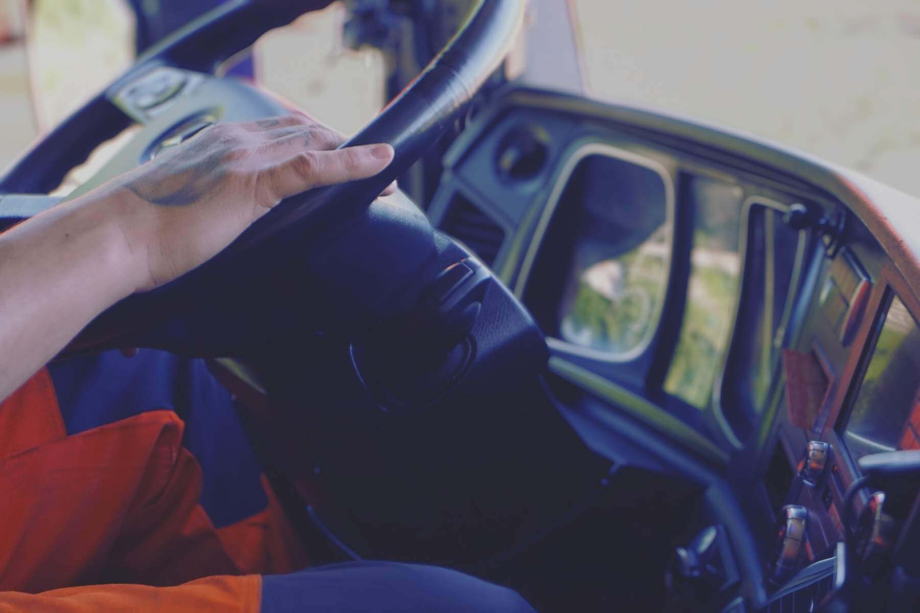 Hand am Lenkrad in einer LKW-Fahrerkabine