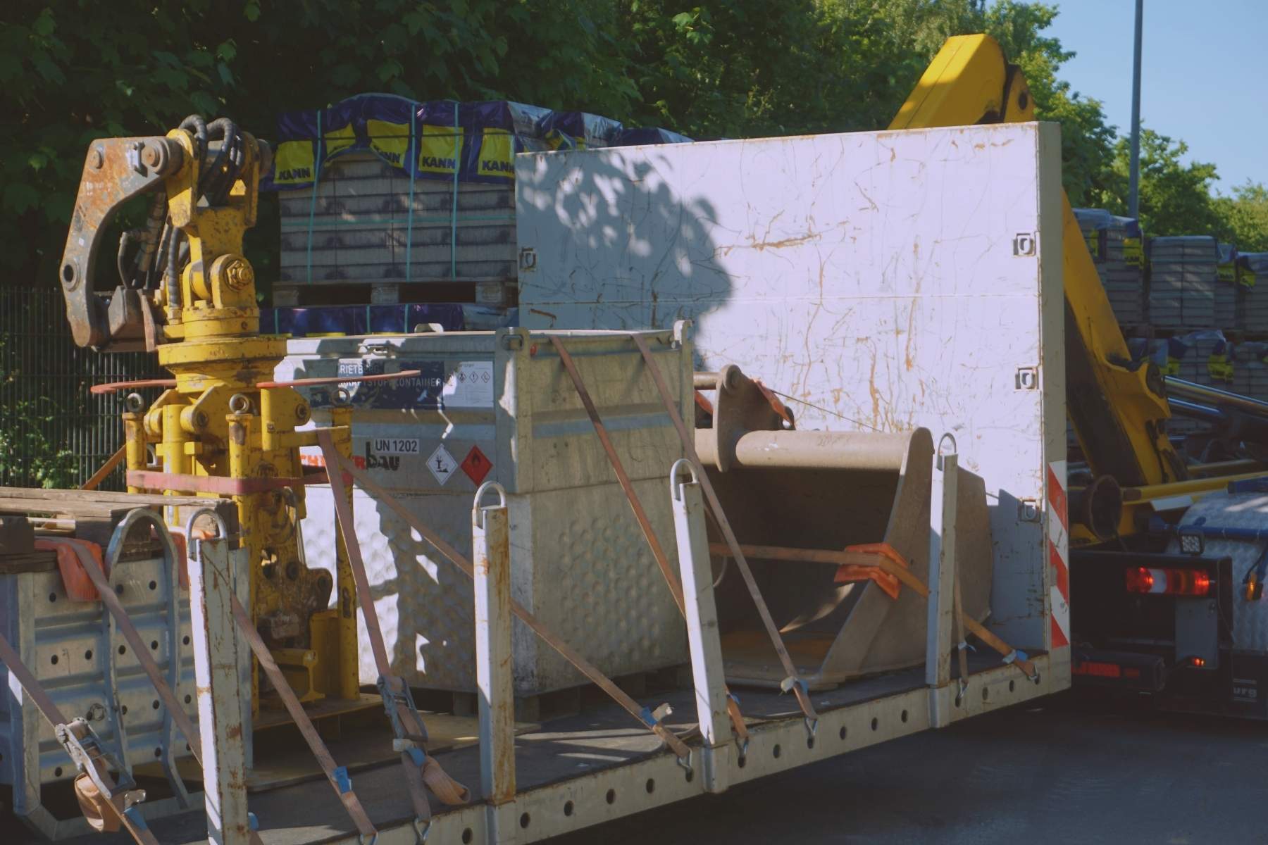 Anbaugeräte und Container auf einem Tieflader, mit Zurrgurten fachgerecht gesichert