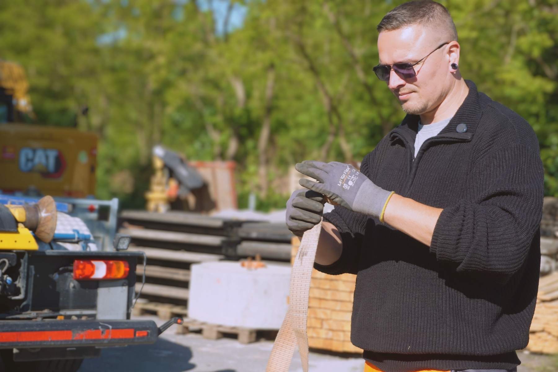 Mitarbeitender mit Schutzhandschuhen bereitet einen Zurrgurt für die Ladungssicherung vor.