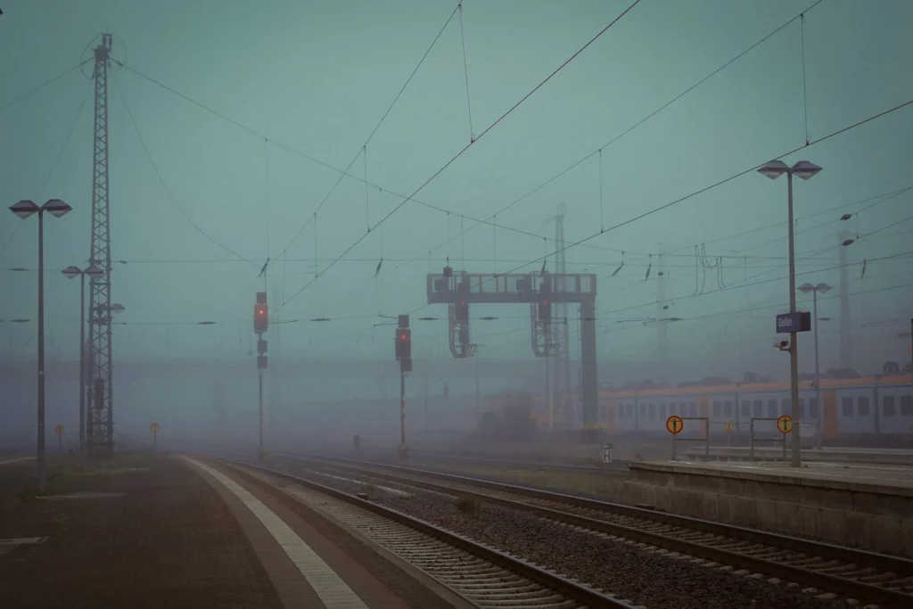 Bahnhofsgleise mit Oberleitungen und Signalanlagen im Nebel
