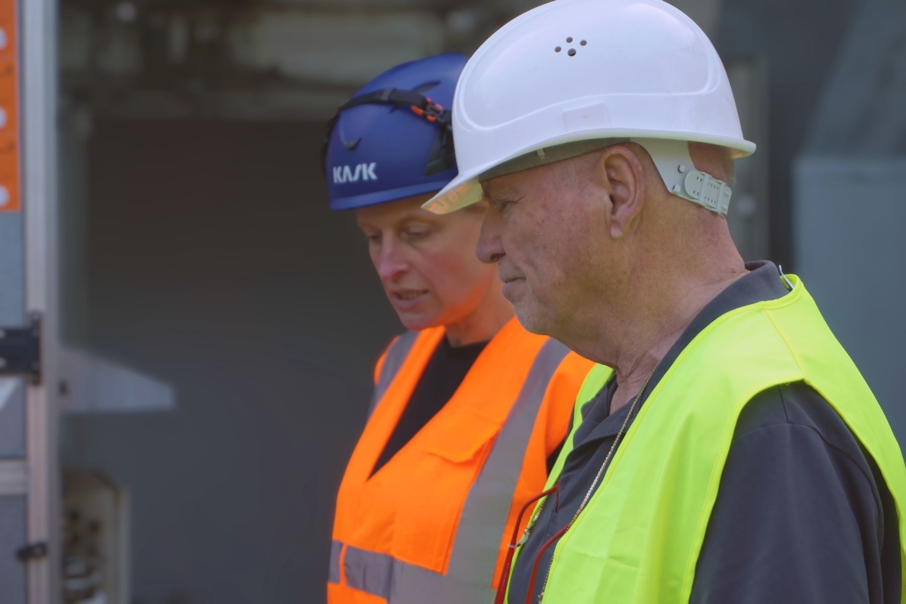 Zwei Mitarbeitende mit Schutzhelm und Warnweste auf der Baustelle