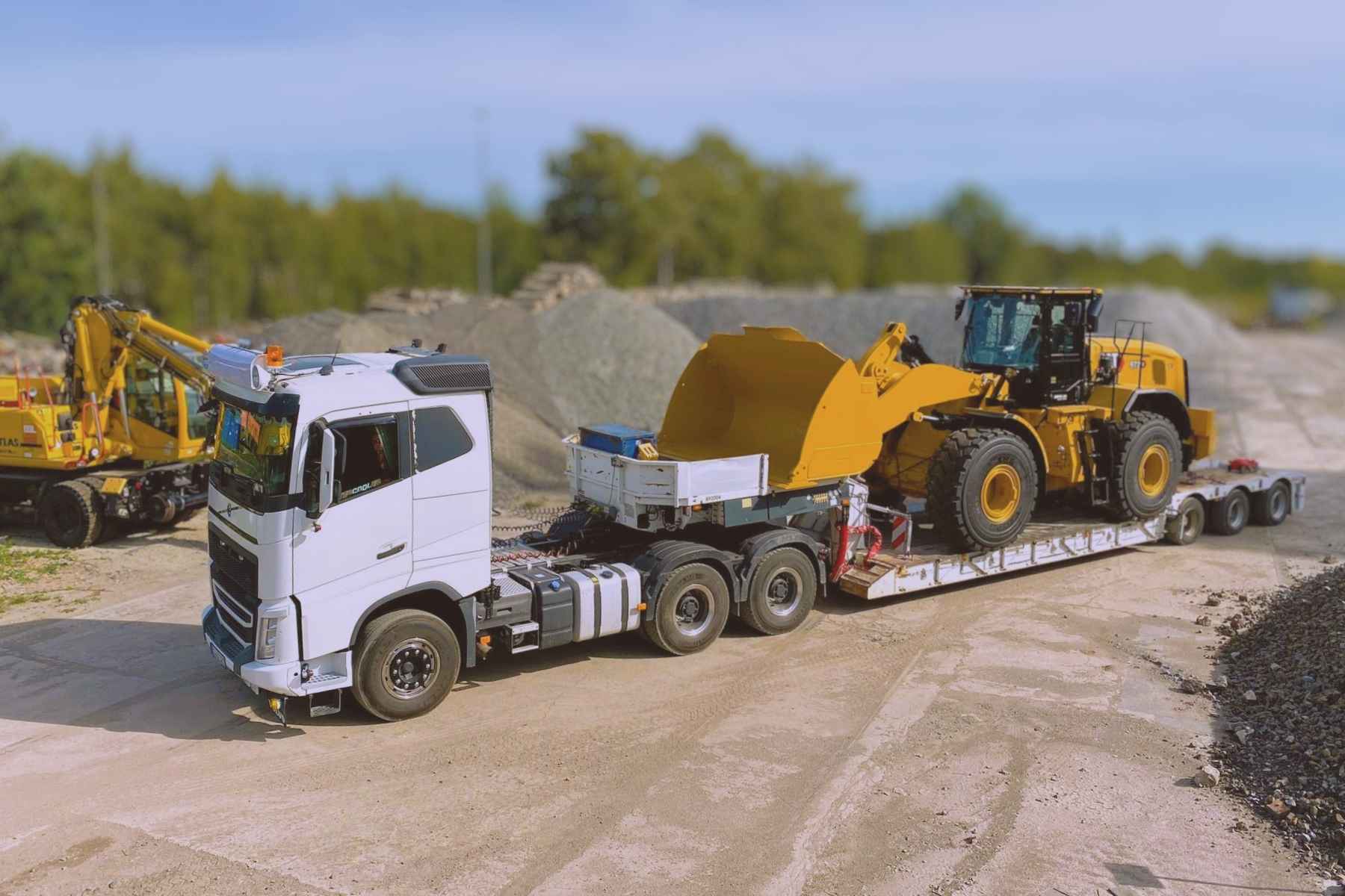 Schwerlasttransport mit Tieflader auf Baustelle, beladen mit großem Radlader für Logistik- und Bauprojekte in NRW.